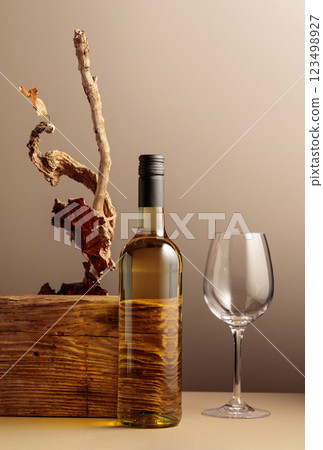Bottle of white wine with a composition of old plank, dry snags, and dried vine leaves. 123498927