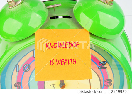 A colorful clock displays a sticky note with the phrase Knowledge is wealth, illustrating the value of education in the realms of business and finance A colorful clock displays a sticky note with the phrase Knowledge is wealth, illustrating the value of education in the realms of business and finance 123499201