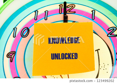 A clock shows the time as a yellow sticky note states knowledge unlocked, emphasizing the connection between education, business, and finance for success A clock shows the time as a yellow sticky note states knowledge unlocked, emphasizing the connection between education, business, and finance for success 123499202