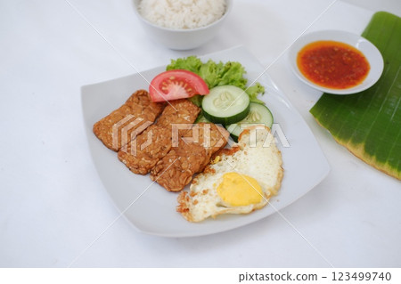 Fried tempeh cutlet with rice and fried egg on white plate Fried tempeh cutlet with rice and fried egg on white plate 123499740