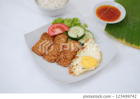 Fried tempeh cutlet with rice and fried egg on white plate Fried tempeh cutlet with rice and fried egg on white plate 123499742