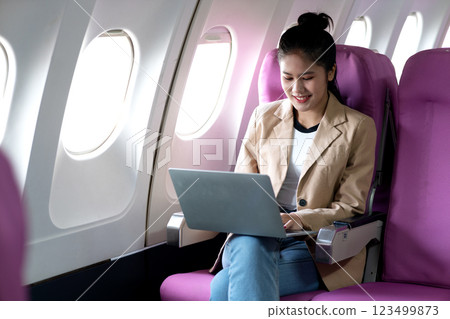 young businesswoman uses laptop while flying airplane for work young businesswoman uses laptop while flying airplane for work 123499873