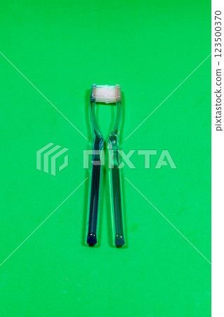 Two toothbrushes facing each other on a green surface 123500370