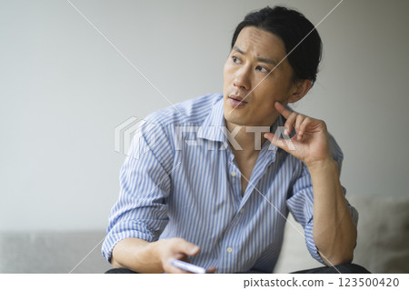 A man in his 40s holding a smartphone A man in his 40s holding a smartphone 123500420