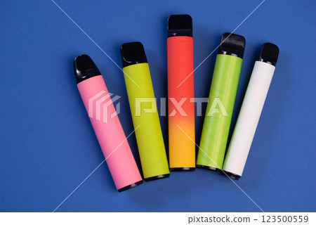 Layout of colorful disposable electronic cigarettes on a dark blue background. The concept of modern smoking, Top view 123500559