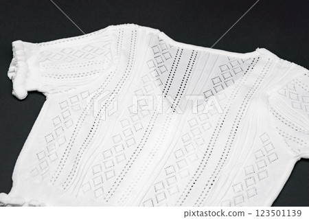 close up to flat White knitwear tshirt shape on black background with studio light. 123501139