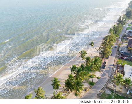 The ariel view of the clear sky with palm trees, fine sand and foam waves splashed to serene beach in Chumphon, Thailand. The ariel view of the clear sky with palm trees, fine sand and foam waves splashed to serene beach in Chumphon, Thailand. 123501426