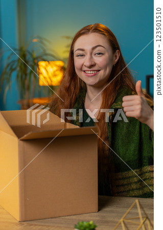 Happy woman shopper unpacking cardboard box delivery parcel online shopping purchase at home office 123501510