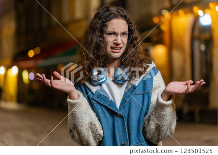 Confused girl feeling embarrassed about ambiguous question having doubts no idea on city street 123501525
