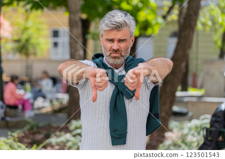 Mature man showing dislike thumbs down sign gesture expressing discontent disapproval dissatisfied Mature man showing dislike thumbs down sign gesture expressing discontent disapproval dissatisfied 123501543