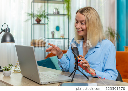 Happy blogger woman recording podcast at table giving workshop webinar speaking at microphone laptop Happy blogger woman recording podcast at table giving workshop webinar speaking at microphone laptop 123501578