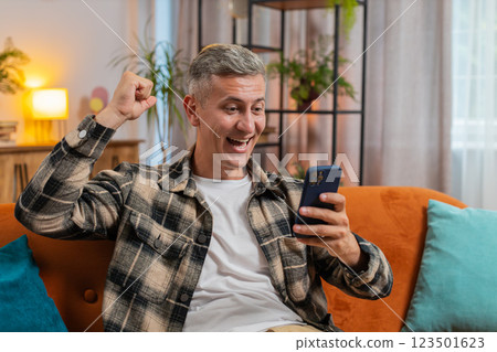 Surprised excited man winner holding smartphone reading good news amazed by online game casino win 123501623