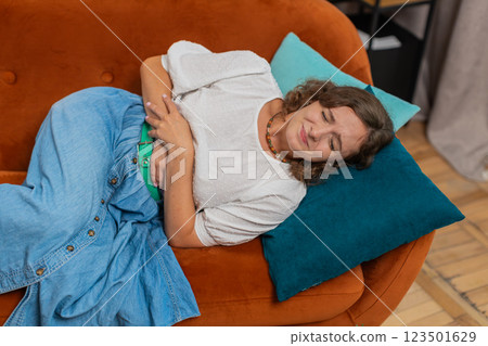 Sick ill young woman lady suffering from period cramps, painful stomach ache on sofa couch at home Sick ill young woman lady suffering from period cramps, painful stomach ache on sofa couch at home 123501629
