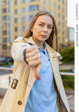 Upset mature Caucasian woman showing thumb down expressing discontent on downtown city street Upset mature Caucasian woman showing thumb down expressing discontent on downtown city street 123501931