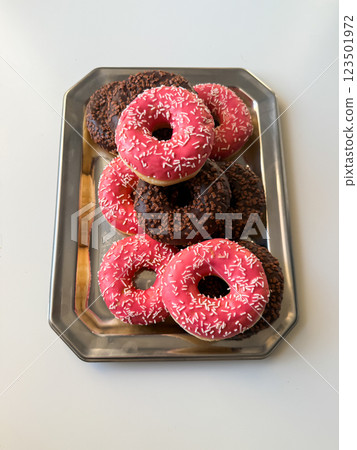 Pink and brown donuts on metal tray top view 123501972