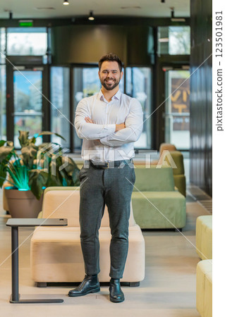 Portrait of happy young businessman with arms crossed looking at camera in modern office hotel lobby Portrait of happy young businessman with arms crossed looking at camera in modern office hotel lobby 123501981