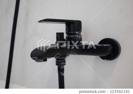 Intense limescale on a black bathroom faucet 123502191