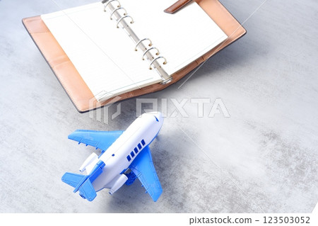 Image of an airplane and an open ring organizer planning your next long vacation trip Image of an airplane and an open ring organizer planning your next long vacation trip 123503052