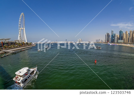 Dubai Marina featuring high rise buildings, a yacht harbor, and a lively promenade 123503746