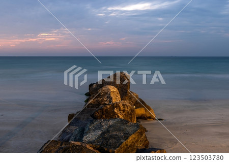 A wave breaker made of rocks illuminated by warm evening light A wave breaker made of rocks illuminated by warm evening light 123503780