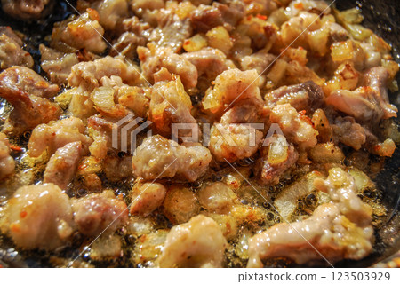 Appetizing fried meat. Meat fried in a pan with onions acquires a yellowish-golden color. 123503929