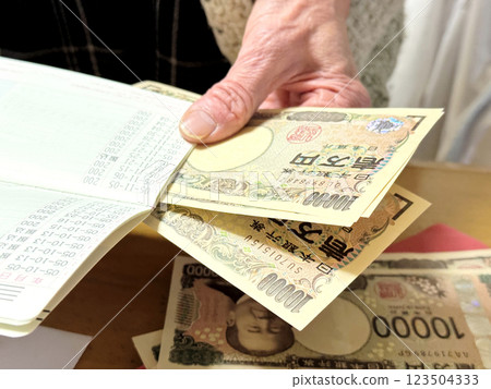 一位老婦人打開存摺，清點新版 10,000 日元鈔票 123504333