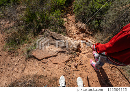 Hiking trail adventure with female child in colorful sneakers on rocky terrain Hiking trail adventure with female child in colorful sneakers on rocky terrain 123504555