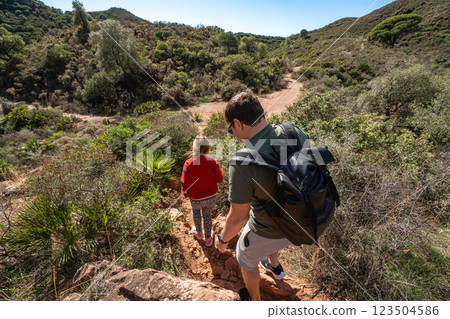 Father and daughter hiking in scenic forest trail on sunny day 123504586