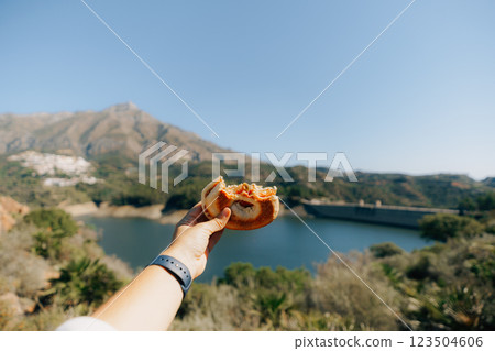 Hand holding sandwich over scenic lake and mountain view 123504606