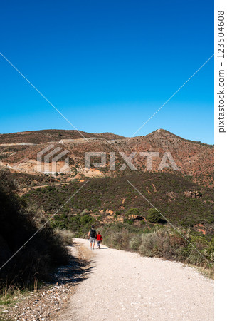 Adults hiking on trail in mediterranean landscape under clear blue sky 123504608