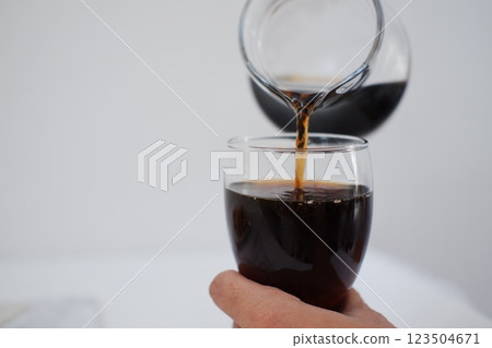 Pouring cola from a jug into a glass on a white background 123504671