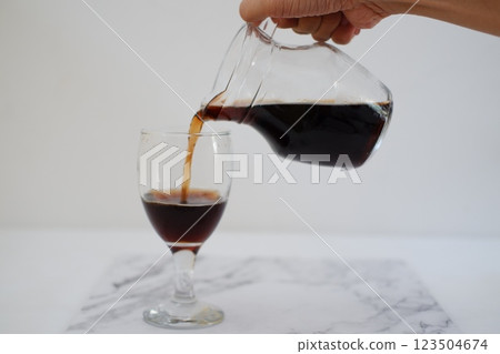 Pouring cola from a jug into a glass on a white background Pouring cola from a jug into a glass on a white background 123504674