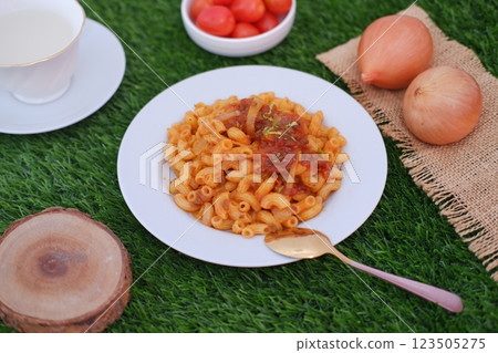 Macaroni with tomato sauce and onions on a white plate. Macaroni with tomato sauce and onions on a white plate. 123505275