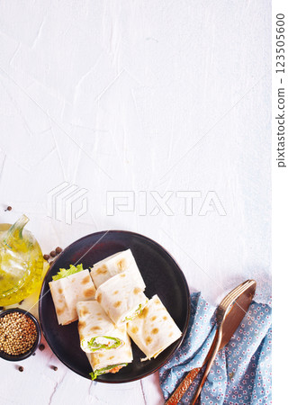 wrapped tortilla sandwich rolls cut in half and ingredients 123505600