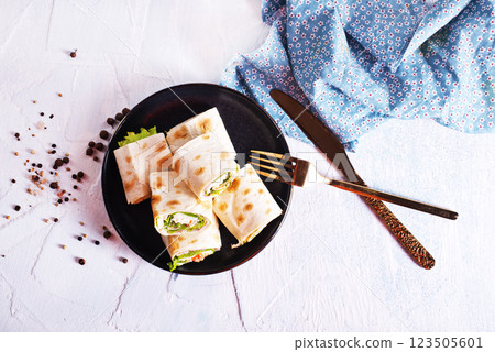 wrapped tortilla sandwich rolls cut in half and ingredients 123505601