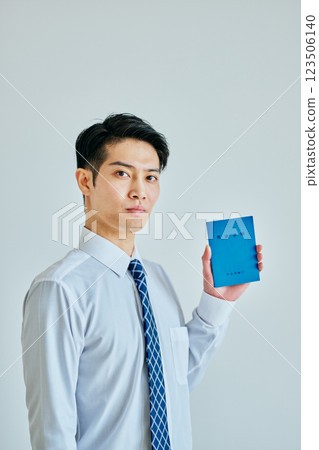 一名 20 多歲的年輕人拿著一本退休金簿 123506140