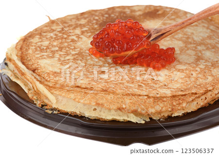 A spoonful of red caviar sits over a stack of fresh pancakes. 123506337