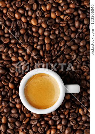 Top view of white espresso cup stands on roasted beans, highlighting rich crema and creating background for coffee lovers. Vertical shoot 123506846