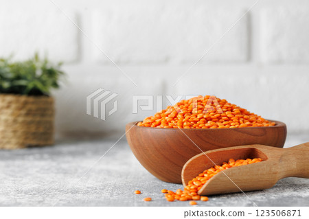 Wooden bowl brimming with rustic red lentils, wooden scoop nestled alongside, spilling grains Wooden bowl brimming with rustic red lentils, wooden scoop nestled alongside, spilling grains 123506871