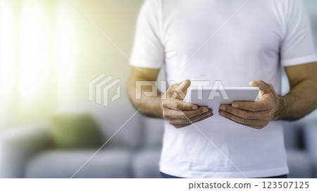 Man Holding Tablet Device in Modern Living Room with Natural Lighting 123507125