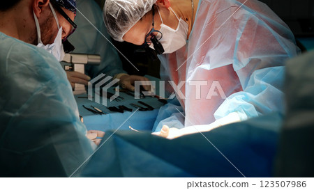 Surgeons in blue scrubs and masks work together in an operating room, using advanced equipment to save lives with precision and care 123507986