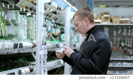 Man carefully reads product labels in the electrical aisle of a hardware store, choosing between various options for diy or professional projects. Ideal for electricians and contractors Man carefully reads product labels in the electrical aisle of a hardware store, choosing between various options for diy or professional projects. Ideal for electricians and contractors 123508067