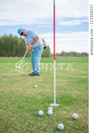 A dedicated golfer is practicing their short game skillfully on the beautiful course A dedicated golfer is practicing their short game skillfully on the beautiful course 123508357