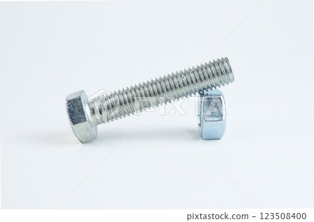 A steel bolt lies next to a hexagonal nut on a plain white surface A steel bolt lies next to a hexagonal nut on a plain white surface 123508400