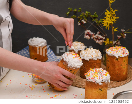a woman sprinkles a traditional Easter cake with sweet sprinkles. 123508462