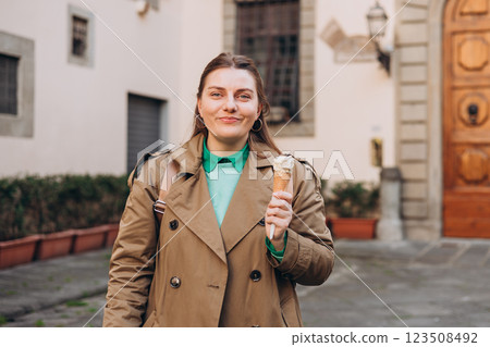 Tasty pistachio ice cream cone in hand. Closeup image of woman hand holding fresh waffle cone with pink ice cream Outdoors, Top Italy food. Lifestyle, travel, people concept. Tasty pistachio ice cream cone in hand. Closeup image of woman hand holding fresh waffle cone with pink ice cream Outdoors, Top Italy food. Lifestyle, travel, people concept. 123508492