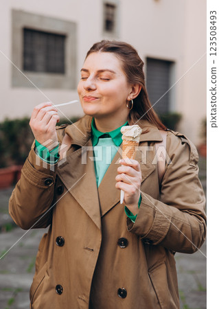 Tasty pistachio ice cream cone in hand. Closeup image of woman hand holding fresh waffle cone with pink ice cream Outdoors, Top Italy food. Lifestyle, travel, people concept. Tasty pistachio ice cream cone in hand. Closeup image of woman hand holding fresh waffle cone with pink ice cream Outdoors, Top Italy food. Lifestyle, travel, people concept. 123508493