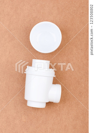 White plastic sink drain trap with threaded ends and plug. 123508802