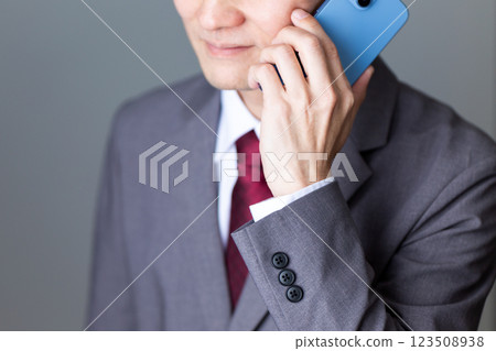A middle-aged male businessman wearing a gray suit and holding a smartphone A middle-aged male businessman wearing a gray suit and holding a smartphone 123508938