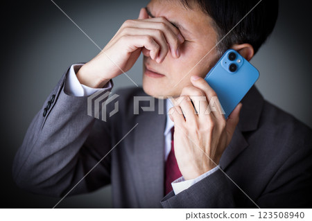 身穿灰色西裝、用智慧型手機通話的中年男性商人 123508940